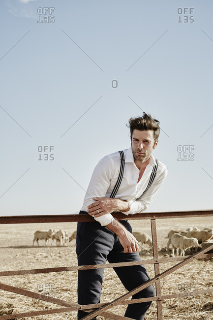 Portrait of man in old-fashioned clothes with flock of sheep in enclosure