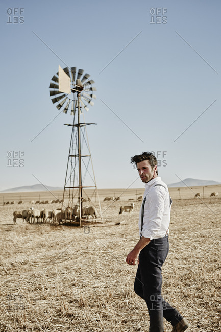 Man in old-fashioned clothes with flock of sheep in the countryside