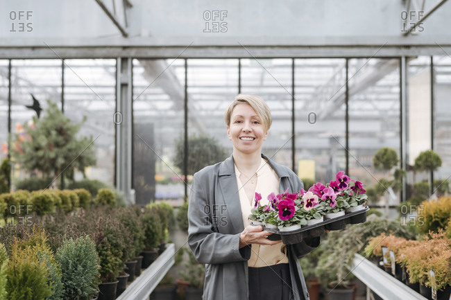Smiling woman with pansies in flower shop