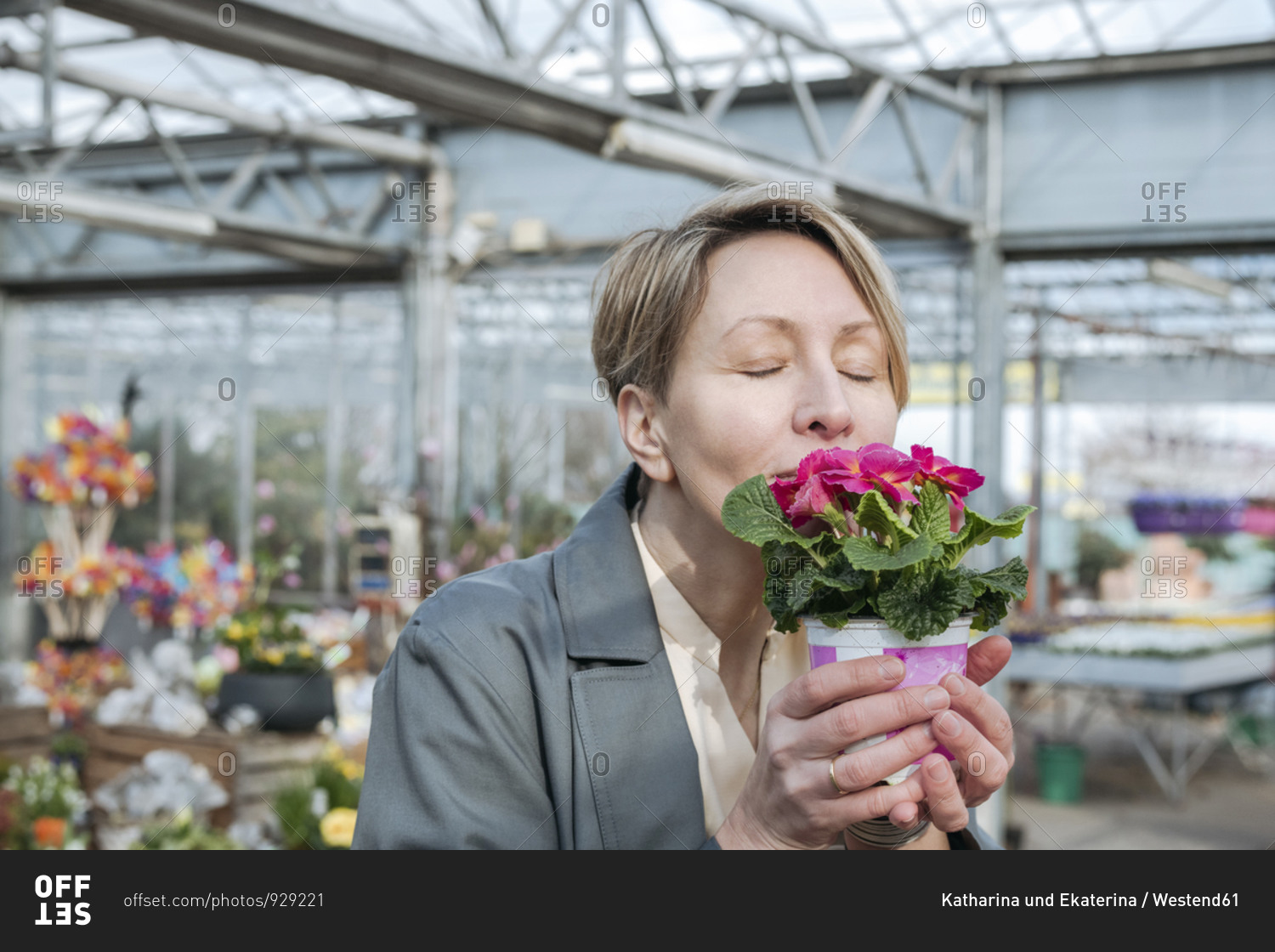 Woman with closed eyes sniffing pink flowers in flower shop