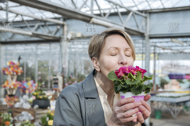 Woman with closed eyes sniffing pink flowers in flower shop