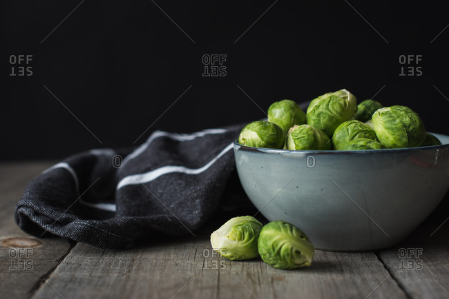 Bowl of Brussels sprouts and napkin on a rustic wooden table.