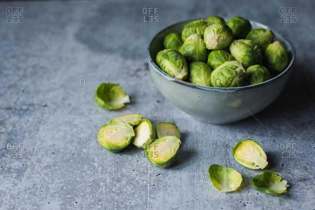 Close up image of a bowl of Brussels sprouts on a cement counter.