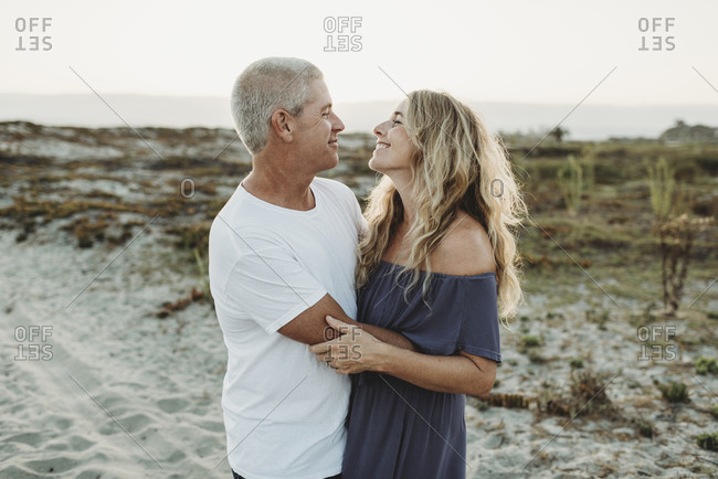 Married couple embracing at beach during sunset