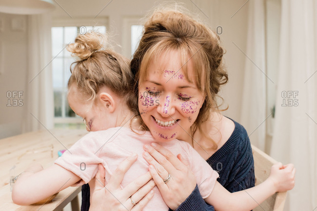 Mother hugging daughter playing dress up with make up and glitter