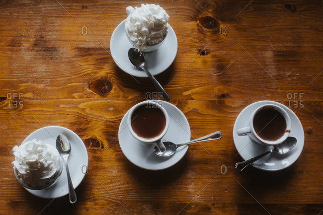 Cups of hot chocolate with and without whipped cream on top of a wooden table
