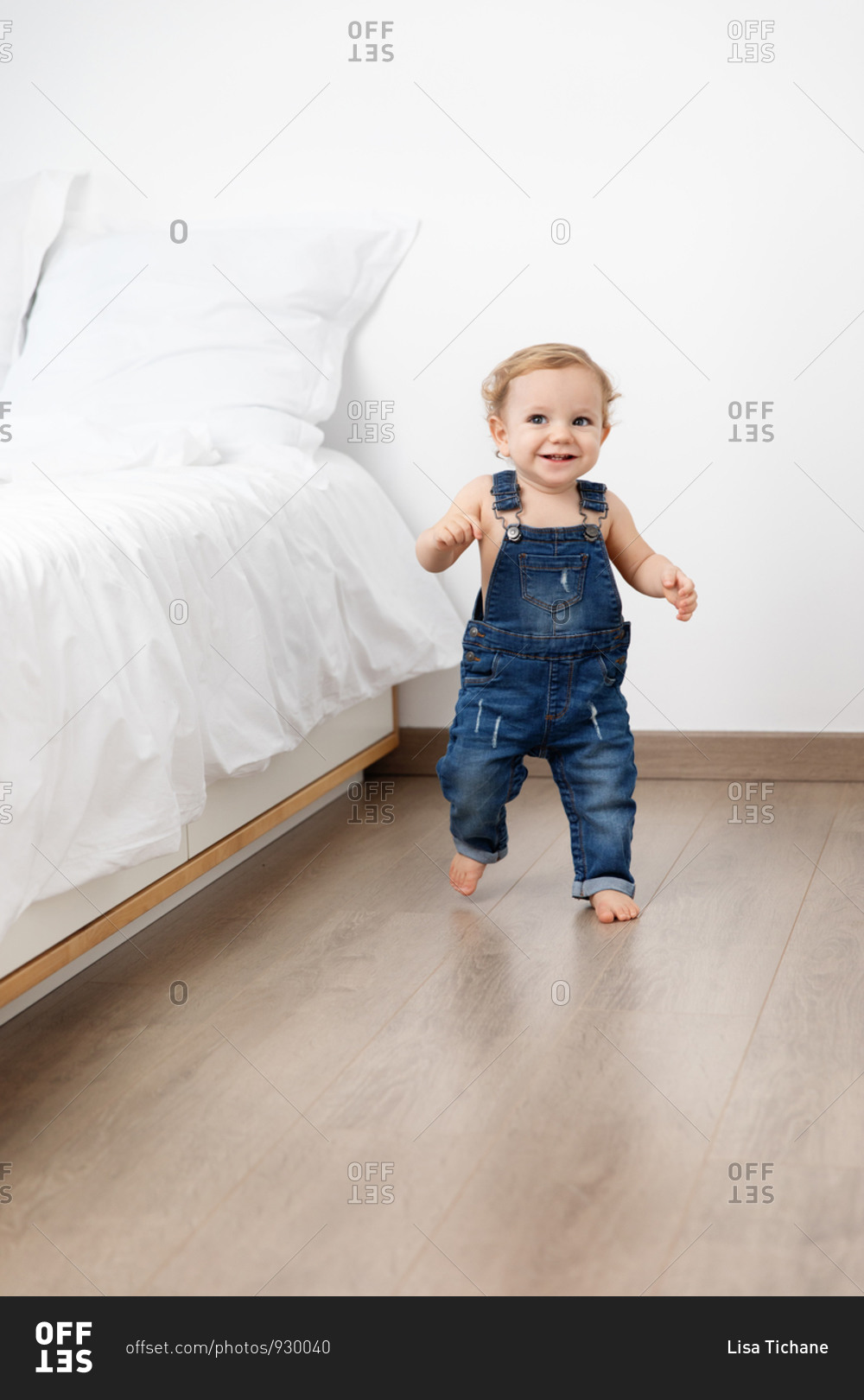 Happy baby making first steps in bedroom