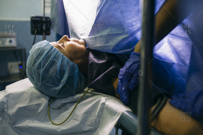 Anesthetist applying blood pressure cuff to patient in operating room