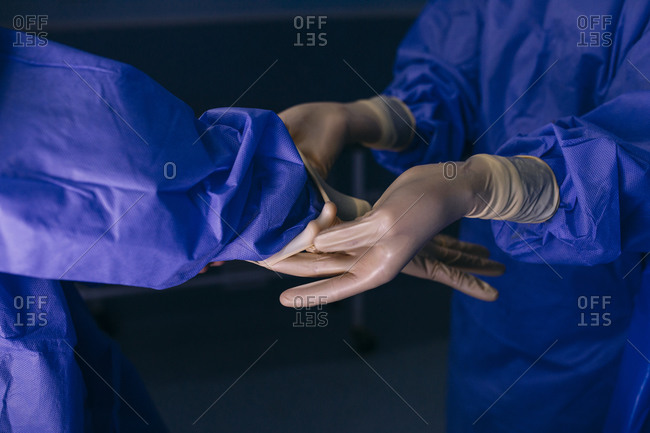 Operating room nurse helping surgeon putting on gloves before an operation