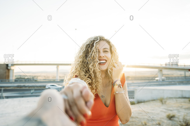 Portrait of happy young woman holding hands at evening twilight