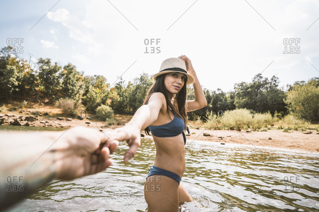 Portrait of young woman wading in a lake holding boyfriend's hand