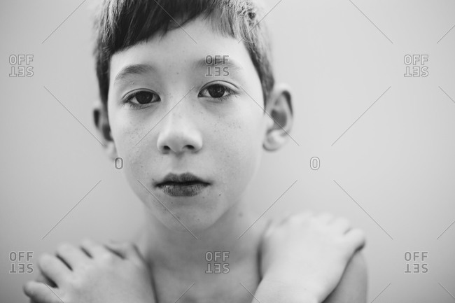 Young boy crossing his arms over his chest in black and white