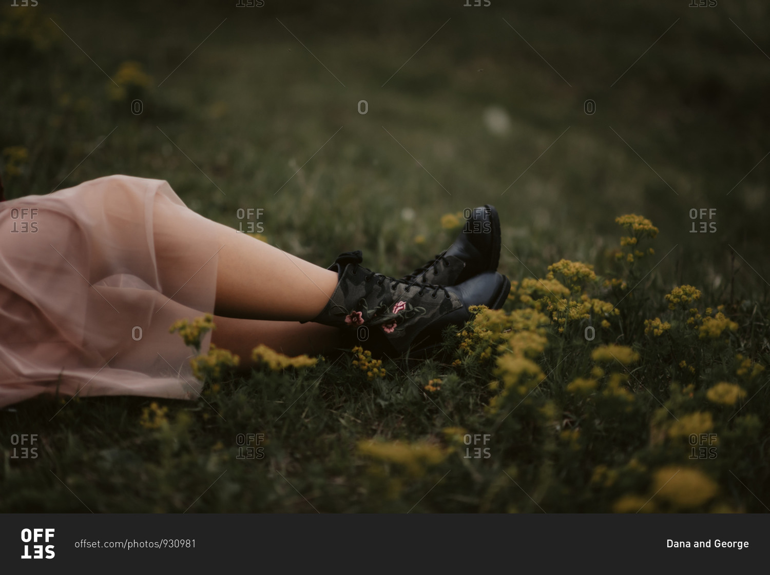 Woman's feet wearing black boots with pink flowers in a field