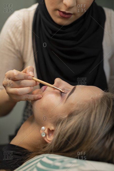 Woman lying down while having makeup applied