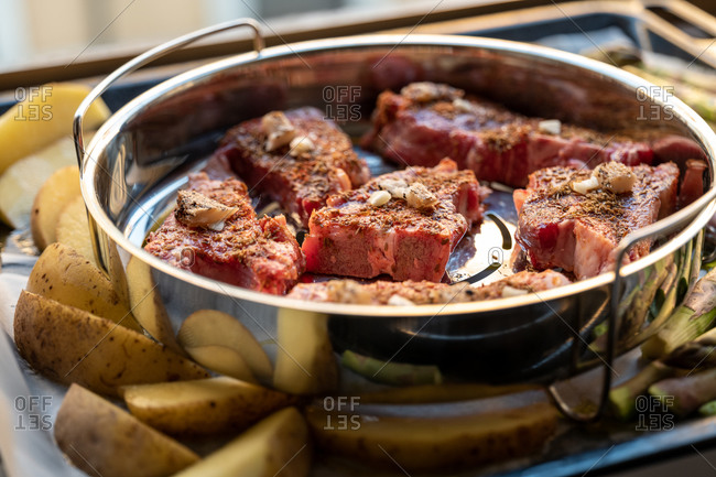 Steaks in a pan surrounded by asparagus and potatoes