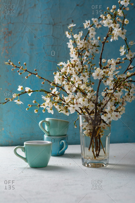 Cherry blossom twigs and coffee mugs on white table
