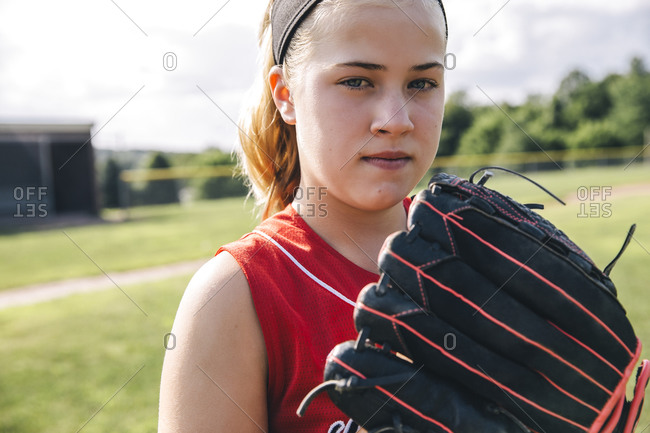 Portrait of confident softball player holding glove on baseball field