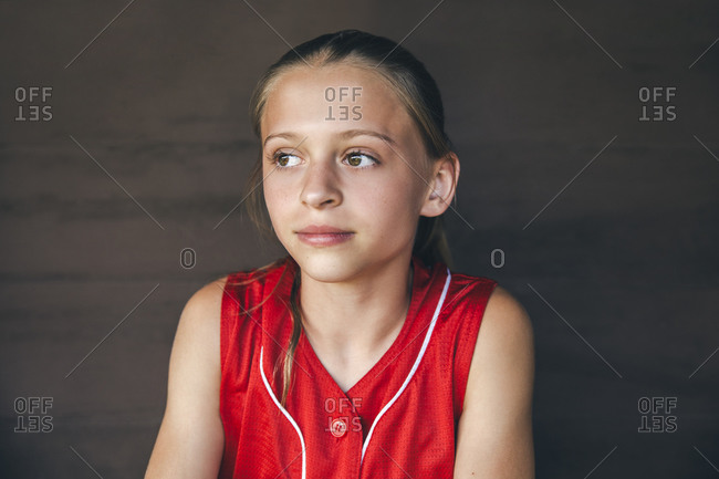Portrait of teenage softball player sitting in dugout