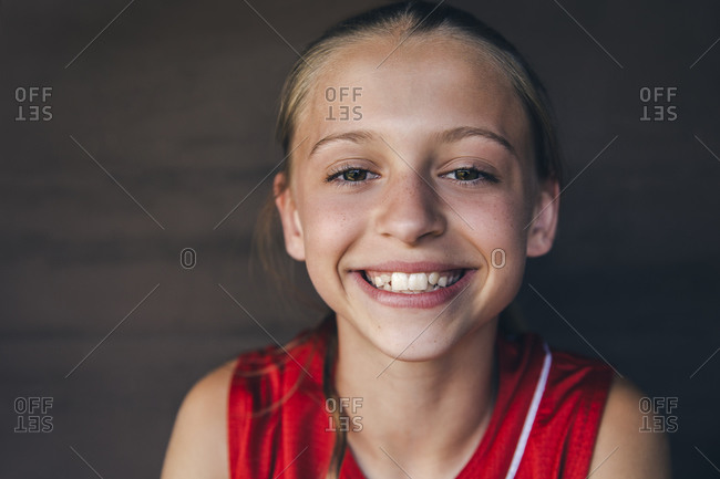 Portrait of happy teenage softball player sitting in dugout