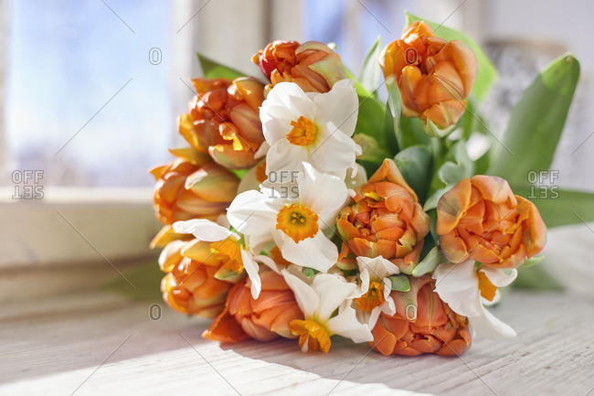 a bouquet of tulips and daffodils on a windowsill