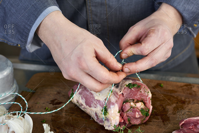 Photo series, step-by-step preparation of a leg of lamb filled with herbs and Provençal vegetables by using a food processor , trussing the leg of lamb