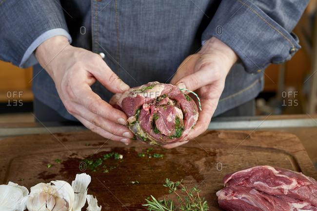 Photo series, step-by-step preparation of a leg of lamb filled with herbs and Provençal vegetables by using a food processor , trussing the leg of lamb