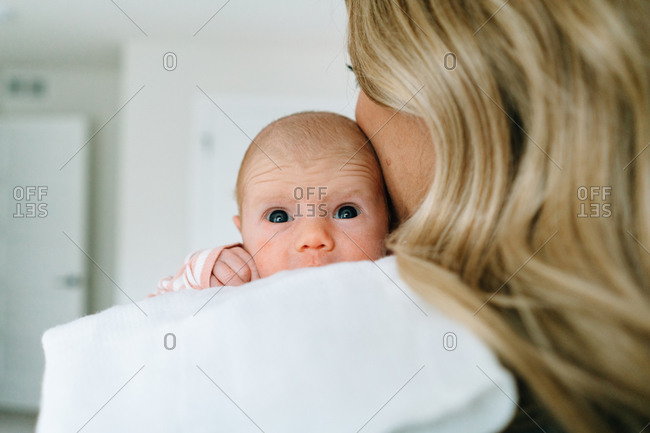 Over the shoulder view of a newborn baby girl being held by her mom
