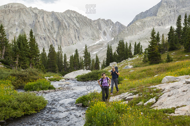 Women hike up creek, meadow to Pierre Lakes, Elk Mountains, Colorado