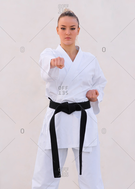 Young female karate expert practicing fighting positions with her kimono