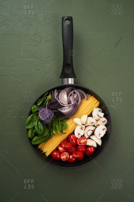 Pasta ingredients in a pan on green textured surface
