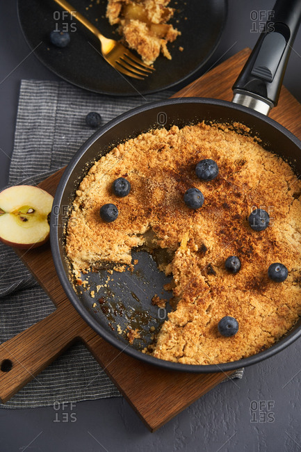 Top view of apple crumble in a skillet topped with blueberries