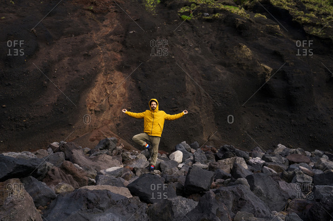 Man standing amidst volcanic rocks in yoga pose- Sao Miguel Island- Azores- Portugal