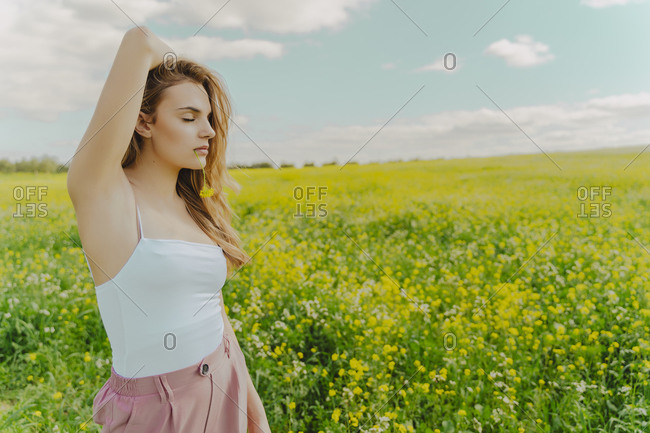 Young woman standing in a flower meadow in spring with blossom in her mouth