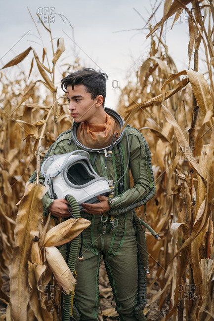 Young spaceman walking through corn field