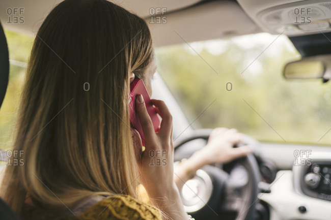 Rear view of young woman talking on the phone inside car