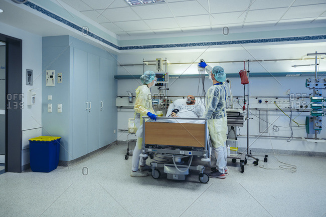 Doctors caring for patient in emergency care unit of a hospital with respiratory equipment
