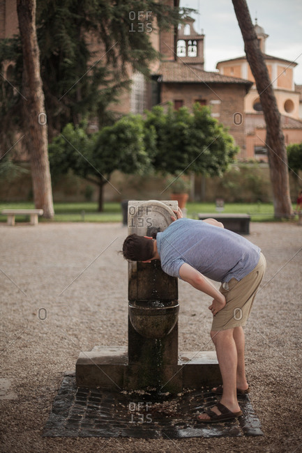 Man drinking from a public water fountain