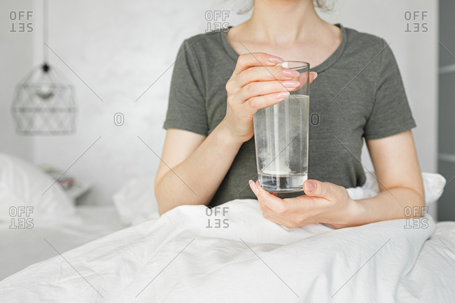 The girl is holding a glass of water with medicine