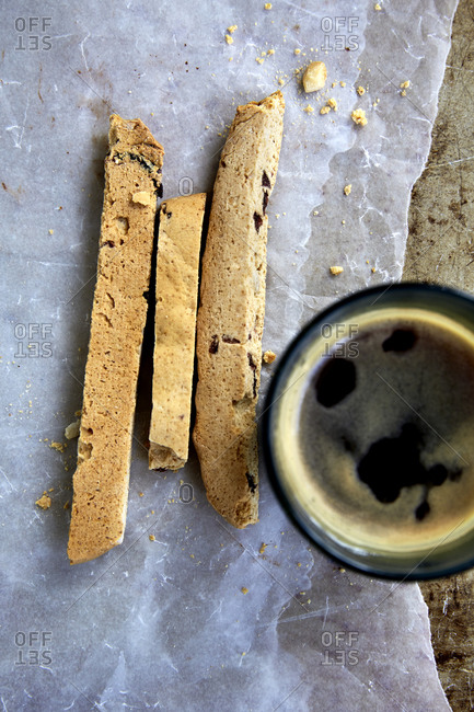 Freshly baked biscotti on wax paper and baking tray with black coffee
