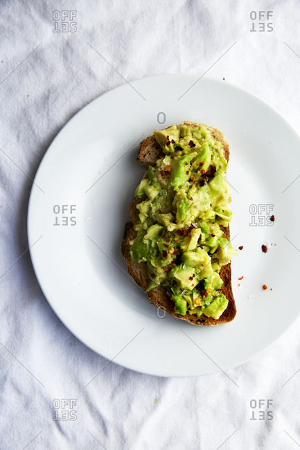 Avocado Toast with chilli flakes on a white plate on white linen