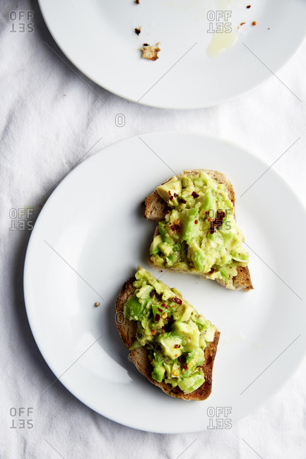 Avocado Toast with chilli flakes on a white plate on white linen