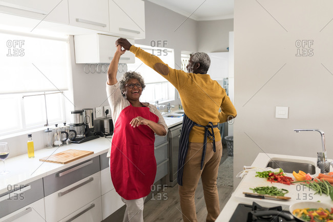 A senior African American couple spending time at home together, social distancing and self isolation in quarantine lockdown during coronavirus covid 19 epidemic, dancing in the kitchen