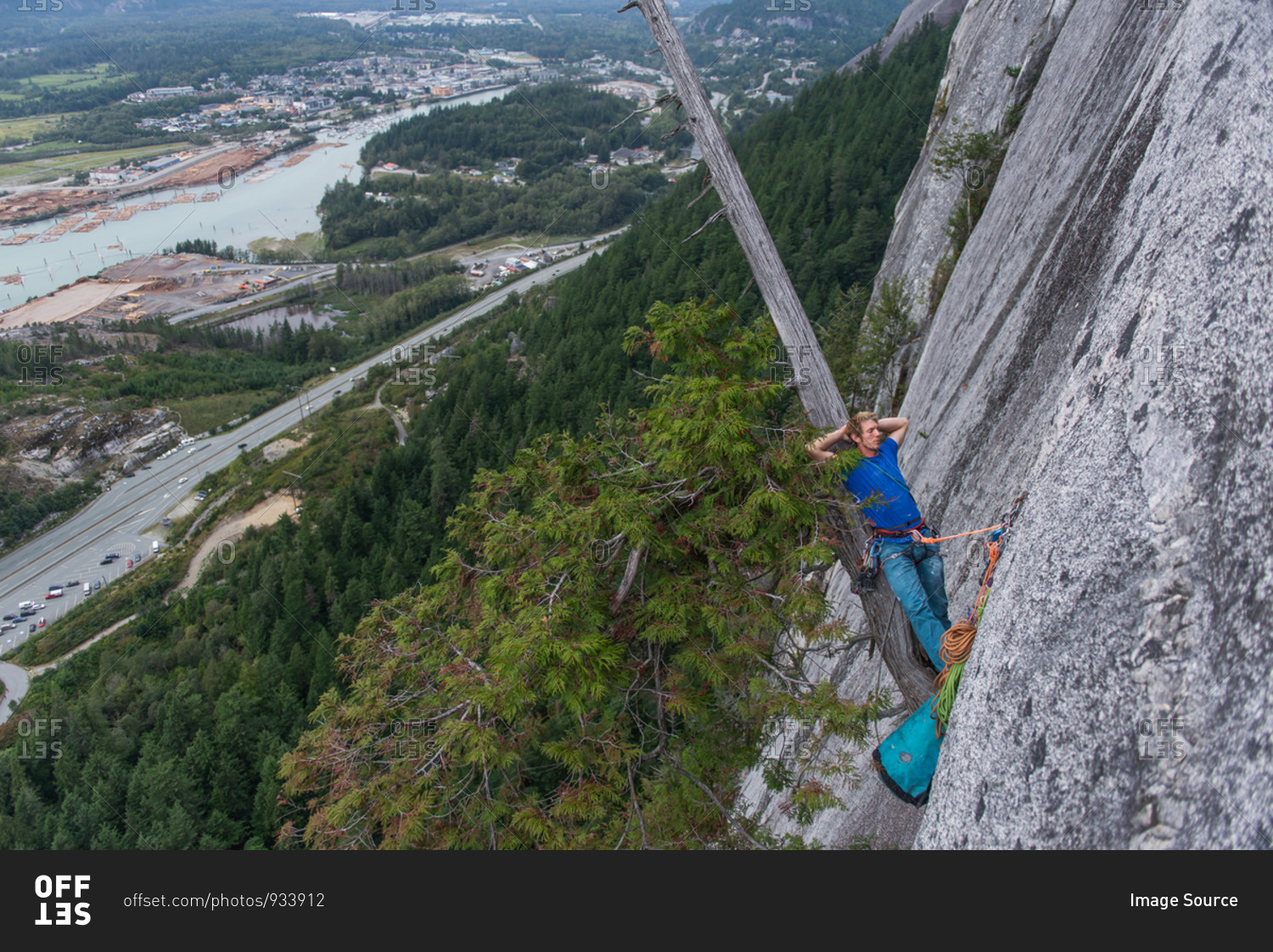Climber sleeping leaning back on a tree growing out of the cliff face, traditional climbing, Sea to Sky corridor, Squamish