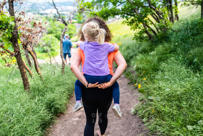 Happy mother giving her son a piggyback ride in the city stock photo