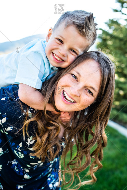 Happy mother giving her son a piggyback ride in the city stock photo