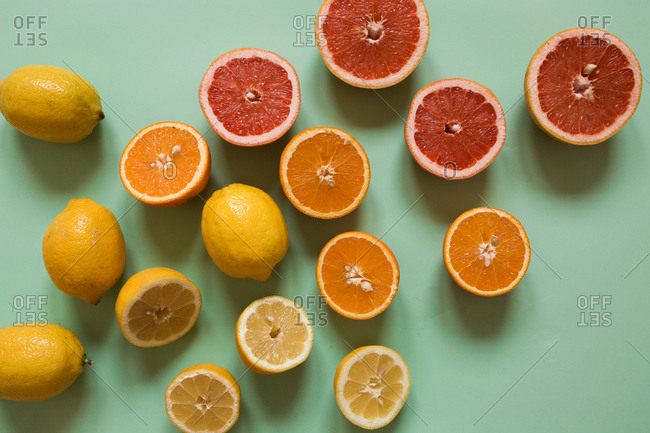 Sliced lemons, oranges and grapefruits on light green background