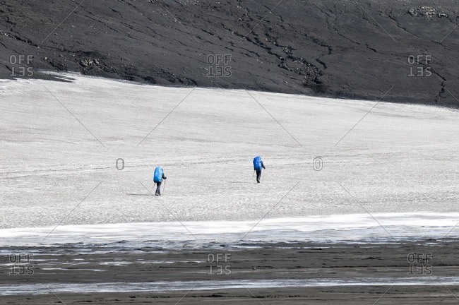 Hikers cross a snow field on the way from Skogar to Landmannalaugar, Iceland, Europe