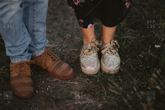 Woman wearing glittery shoes beside a man wearing brown shoes