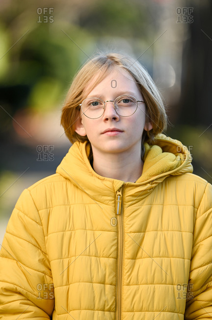 Tween boy with glasses and yellow jacket smiling looking at camera