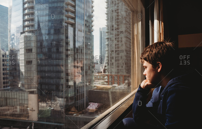 Man looking through window at cityscape stock photo - OFFSET